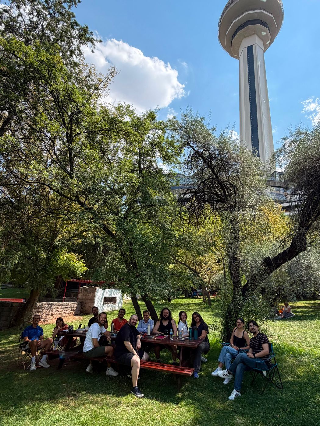 Atakule'nin gölgesinde, ağaçların altındaki masada oturan Inklings & Tea Club üyeleri.