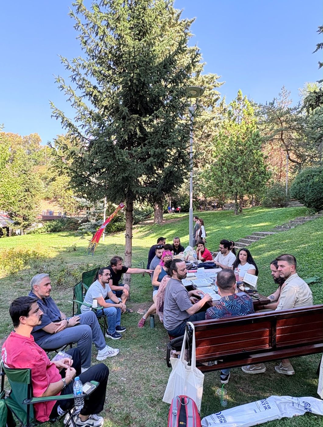 Botanik Park'ta çimlerde sandalye ve banklarda oturan Kitap Kulübü katılımcıları.